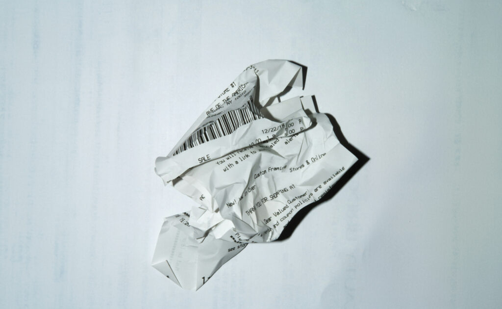 A crumpled paper receipt with printed text and a barcode sits on a plain white background, hinting at the future where practice management software could eliminate such clutter for efficient organization.