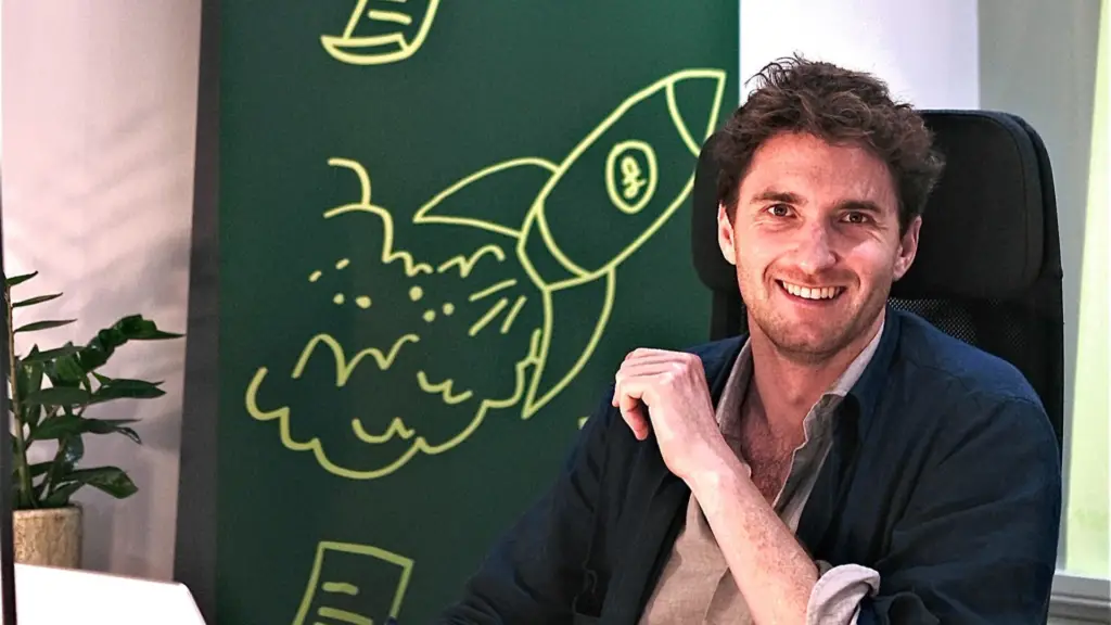 Tom Pope at his desk in front of a chalkboard drawing