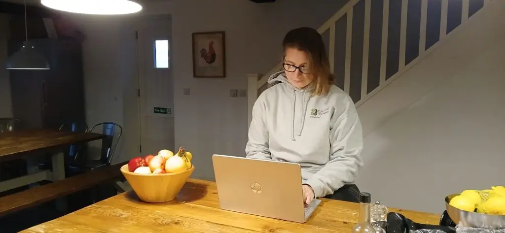 Lucy Brown working on a laptop at a kitchen table